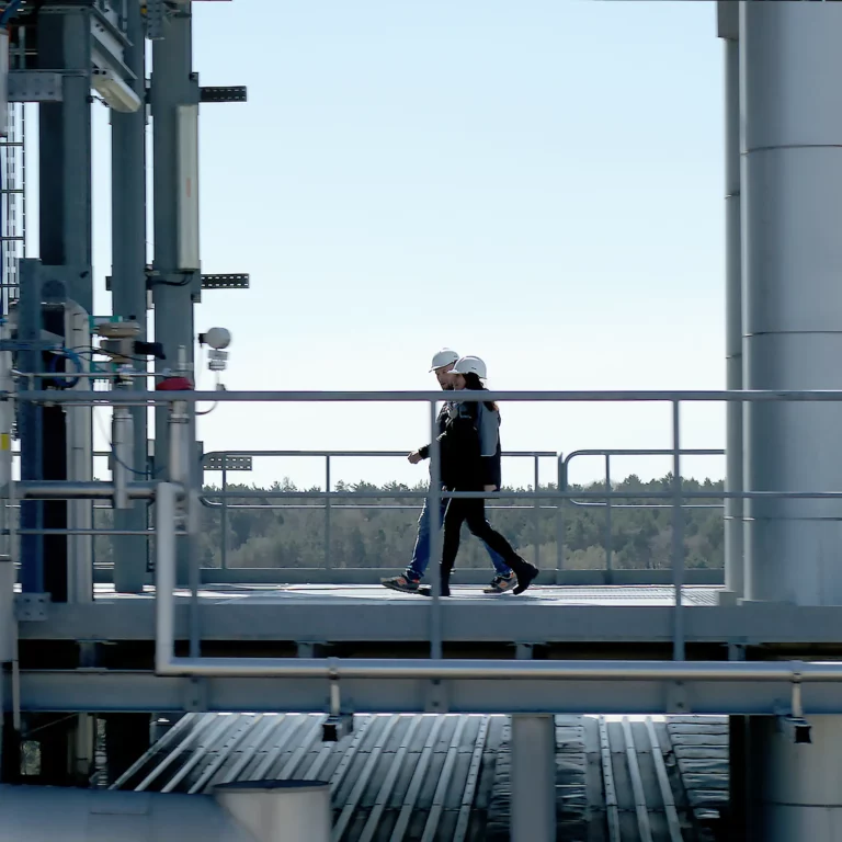 Two employees walk across a platform at the Silane factory